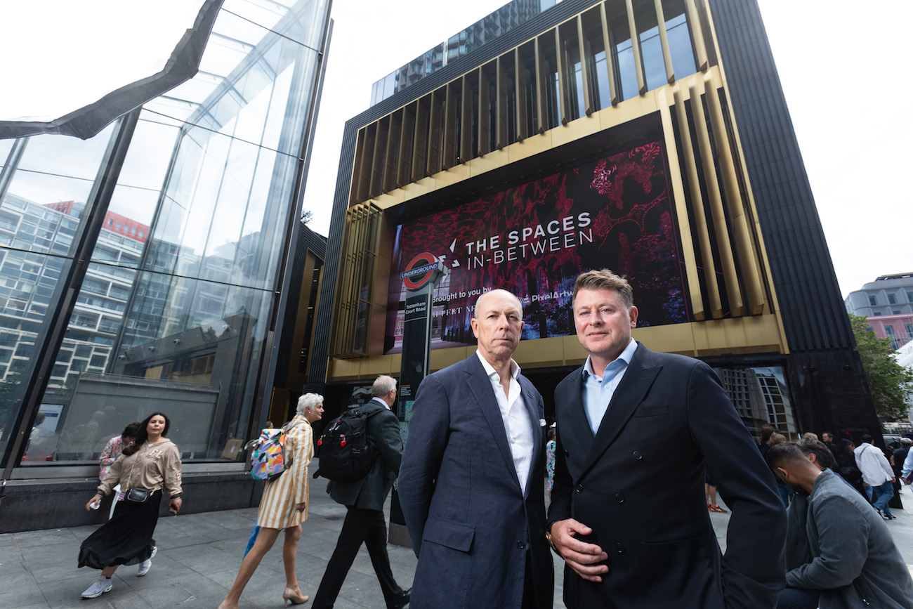 Outernet founders standing in front of The Now building with The Spaces In-Between advert behind