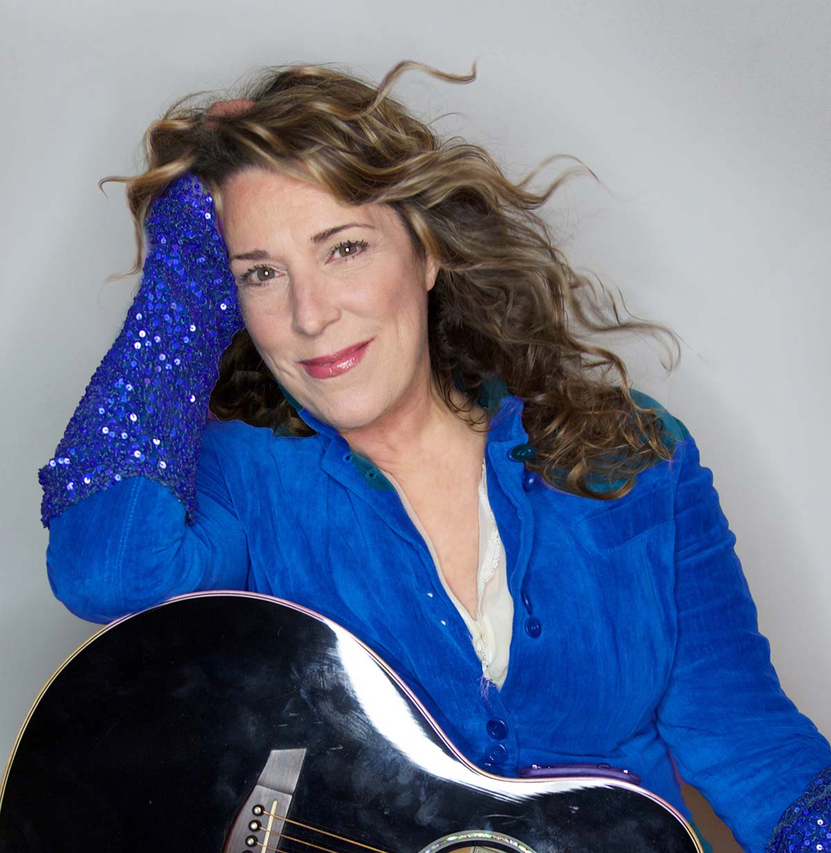 Portrait of Beth Nielsen Chapman leaning on an acoustic guitar