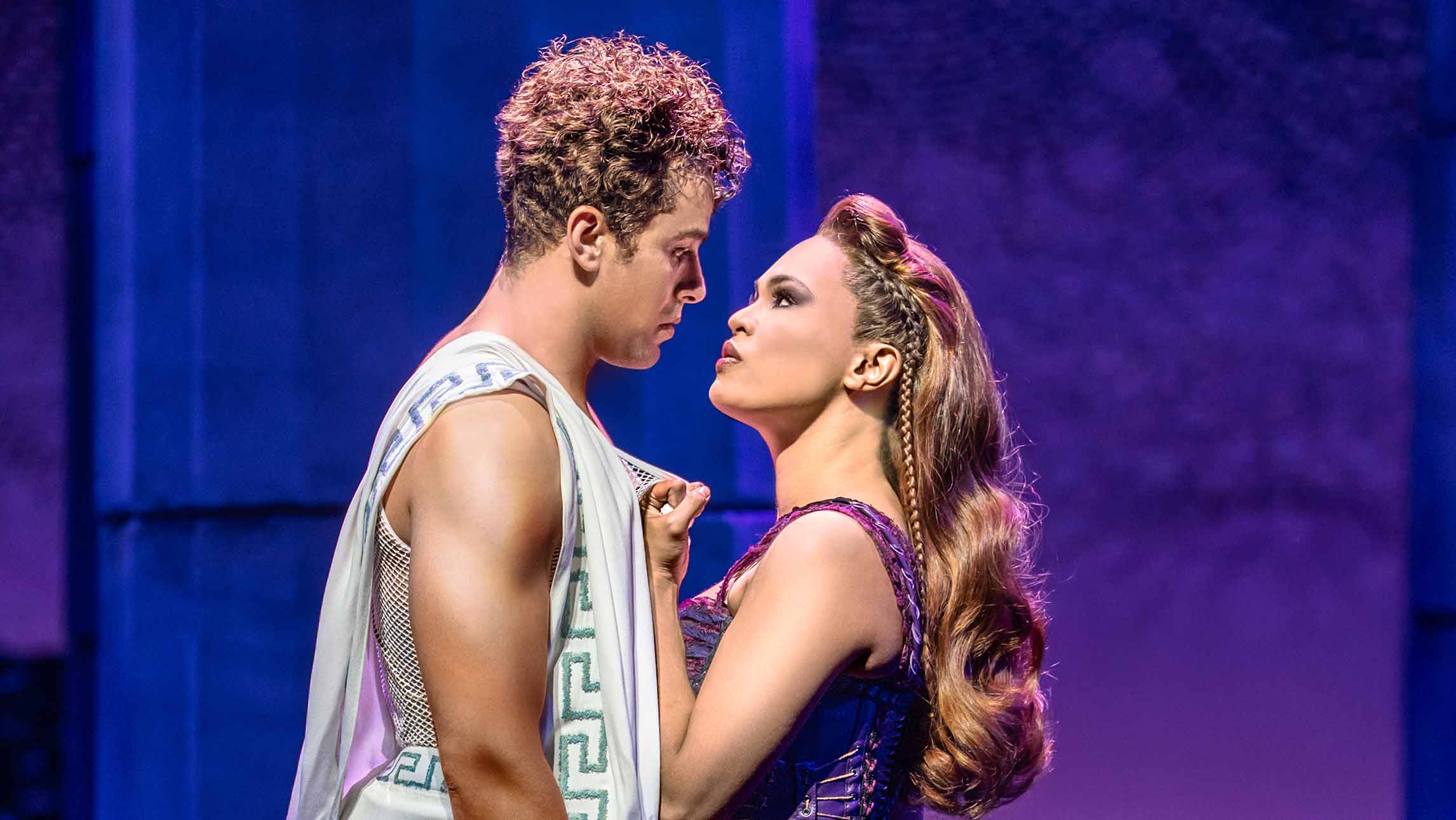 Actors Luke Brady (Hercules) and Mae Ann Jorolan (Meg) on stage in Disney's Hercules Two actors starring deeply into each others eyes