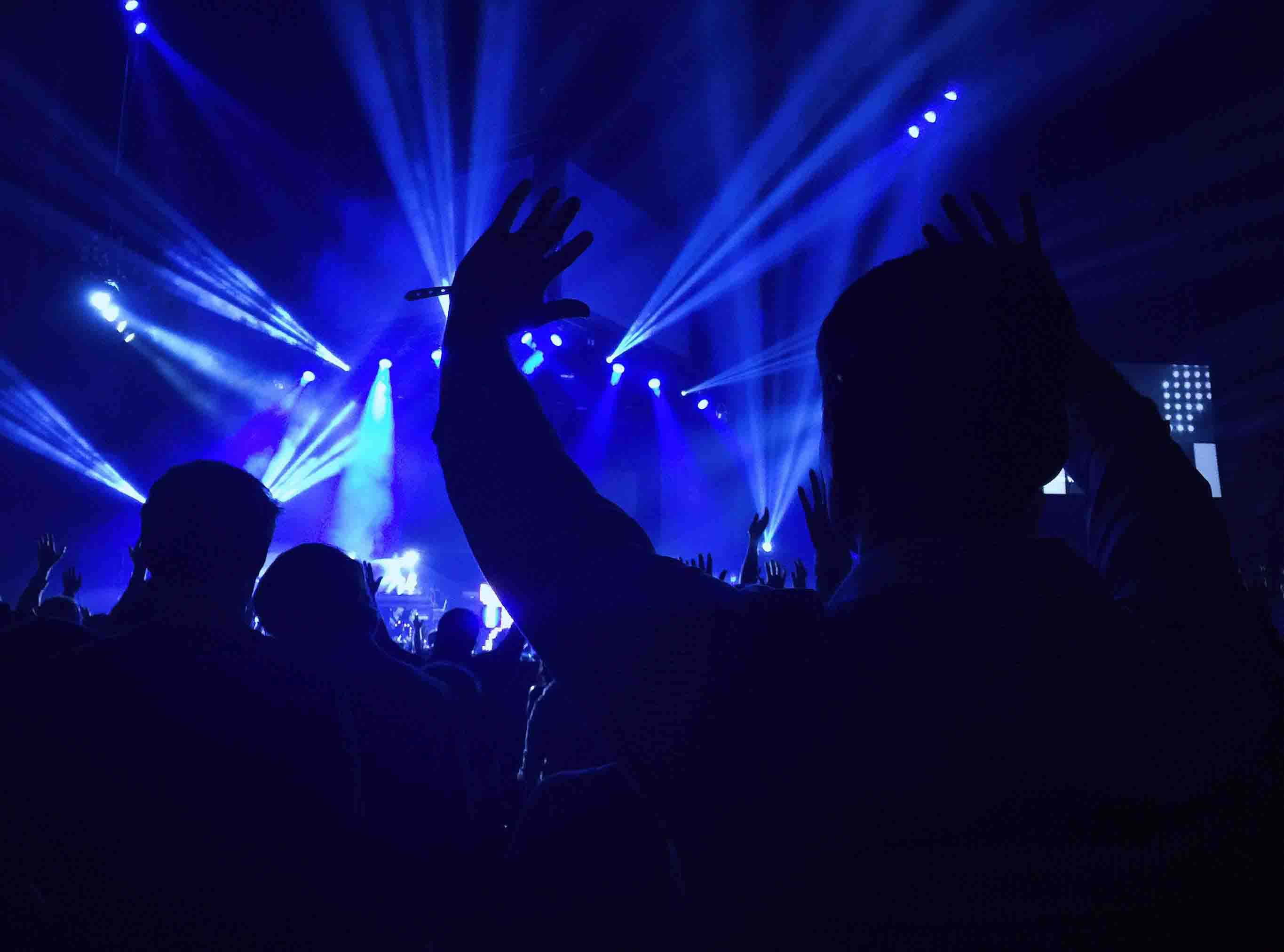 Spectators at a concert with their hands in the air